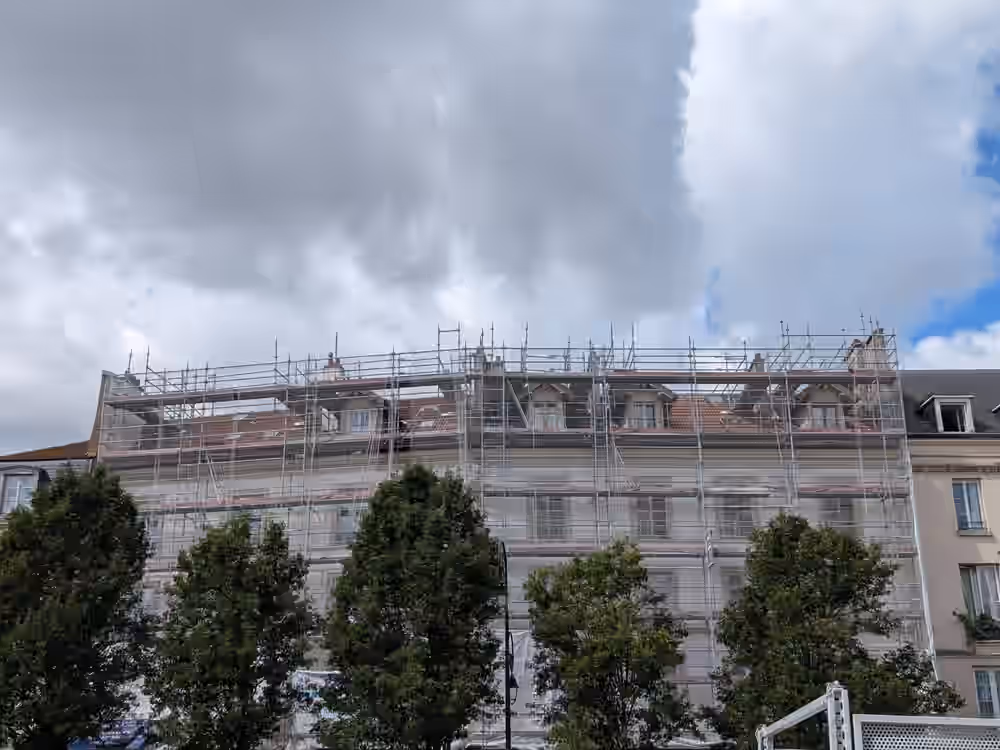 Copropriété de quatre étages sur une place, façade complète sous bâche de protection