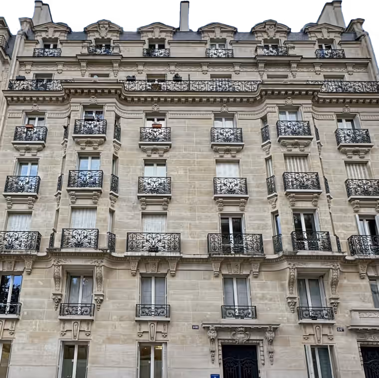 Immeuble haussmannien parisien en pierre de taille, façade sur rue avec balcons en ferronnerie